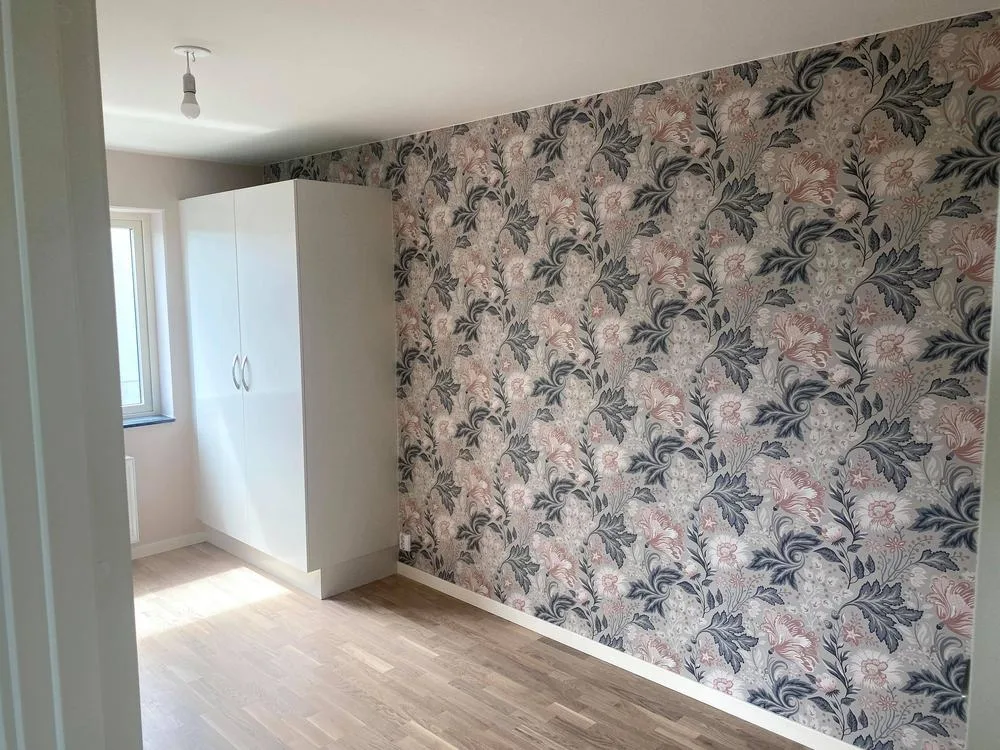Sovrum med blommönstrad tapet på fondväggen