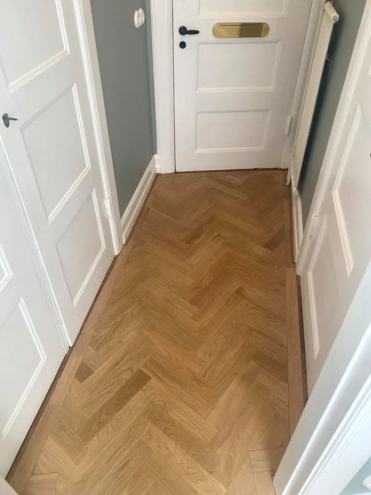 Hall med fiskbensparkett och vita spegeldörrar