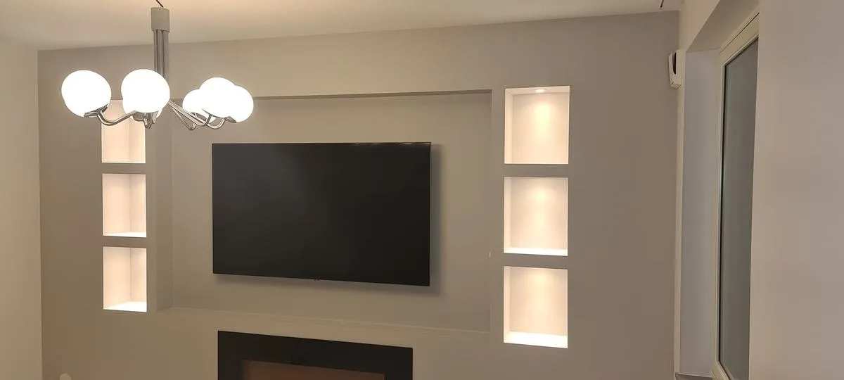 Vägg med belysta nischer runt en TV